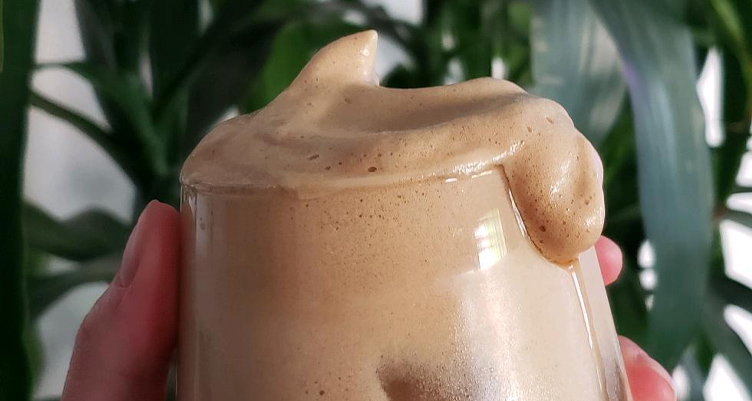 Main tenant une tasse de café fouetté