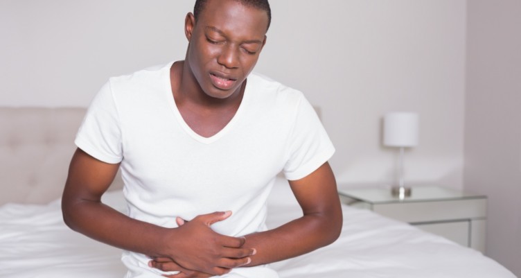 Homme grimaçant au bout du lit.