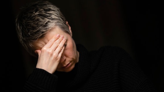 A woman sits holding her hands in front of her face.  © picture alliance / photothek Photo: Thomas Trutschel