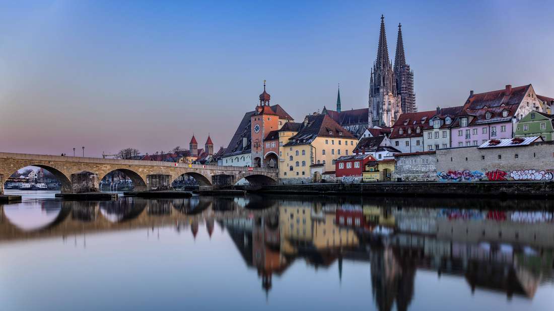 Regensburg in the evening view over the Danube to the Regensburg Cathedral and the stone bridge in Regensburg, Bavaria, Germany 