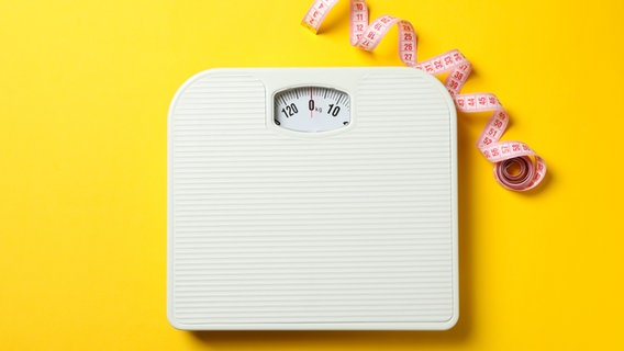 A bathroom scale and tape measure on a yellow background.  © Colourbox Photo: AtlasStudio