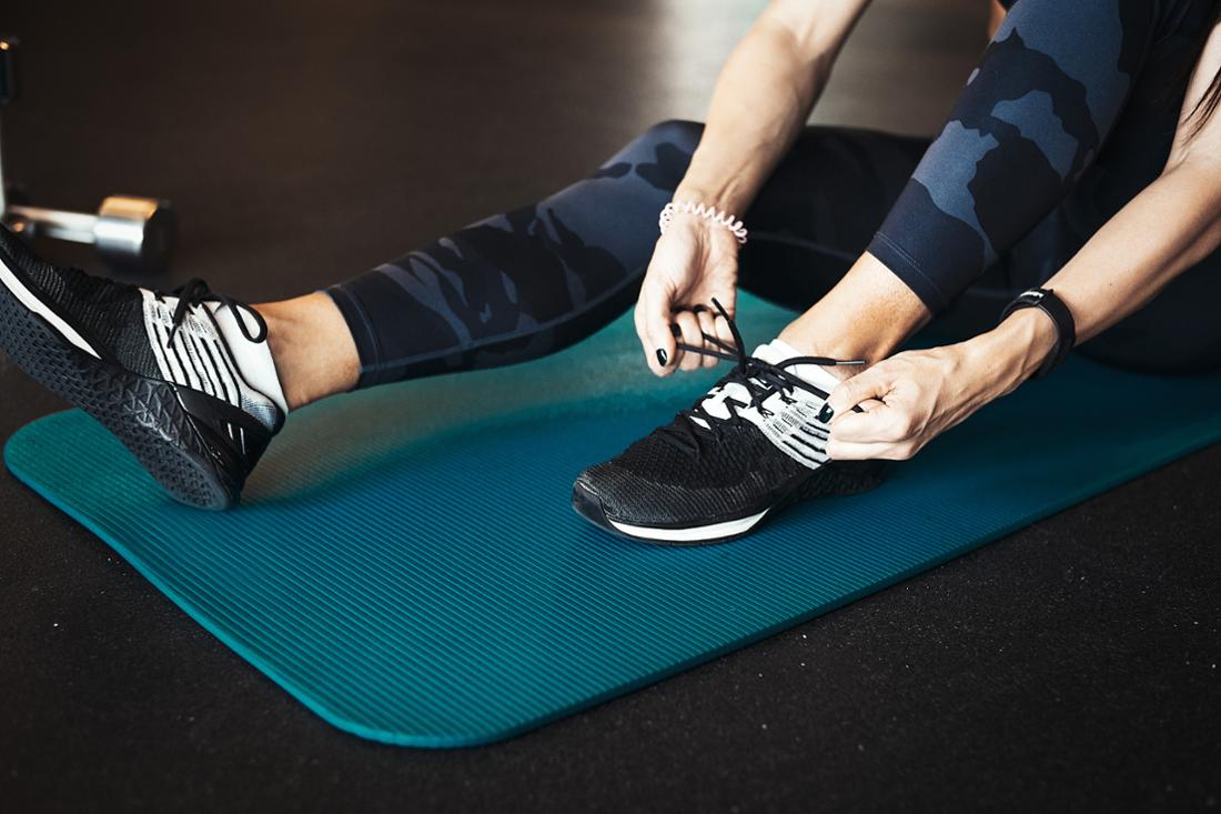 Woman tying her sneakers on a mat