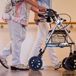 A nurse walks with an elderly lady down a corridor in a nursing home. (Photo: Christoph Schmidt/dpa)  