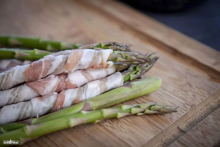 The hit in early summer: Green asparagus wrapped in bacon ends up on the grill. After around 15 minutes at 150 degrees, it is ready to sizzle. - © Grillfürst/Grillfürst/dpa