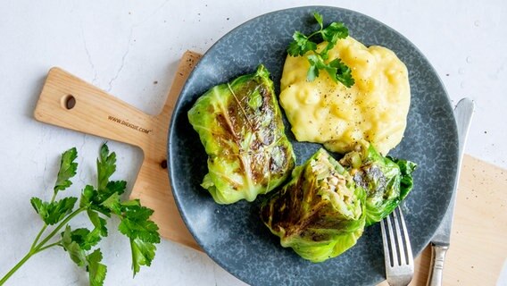 Two pointed cabbage roulades with mashed potatoes on a plate. © NDR Photo: Claudia Timmann