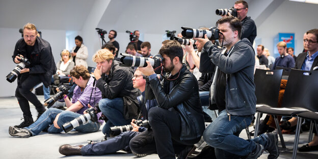 Men stand and crouch with cameras.