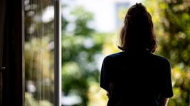 Lonely woman stands at the open window