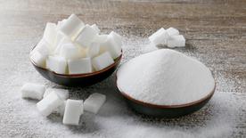 Two bowls of sugar are on a table. 