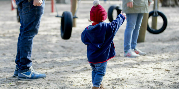 A child stands with his parents on a playground in Volkspark Wilmersdorf. After playgrounds were closed to contain the coronavirus, they are now reopening