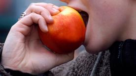 A woman bites into an apple.