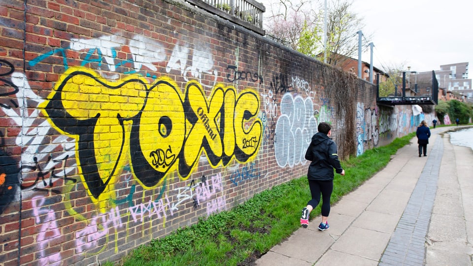 The word “toxic” is sprayed in large yellow letters on a brick wall.